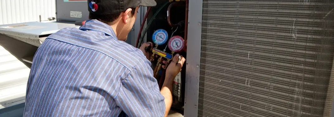 HVAC technician servicing a condenser unit in Posen
